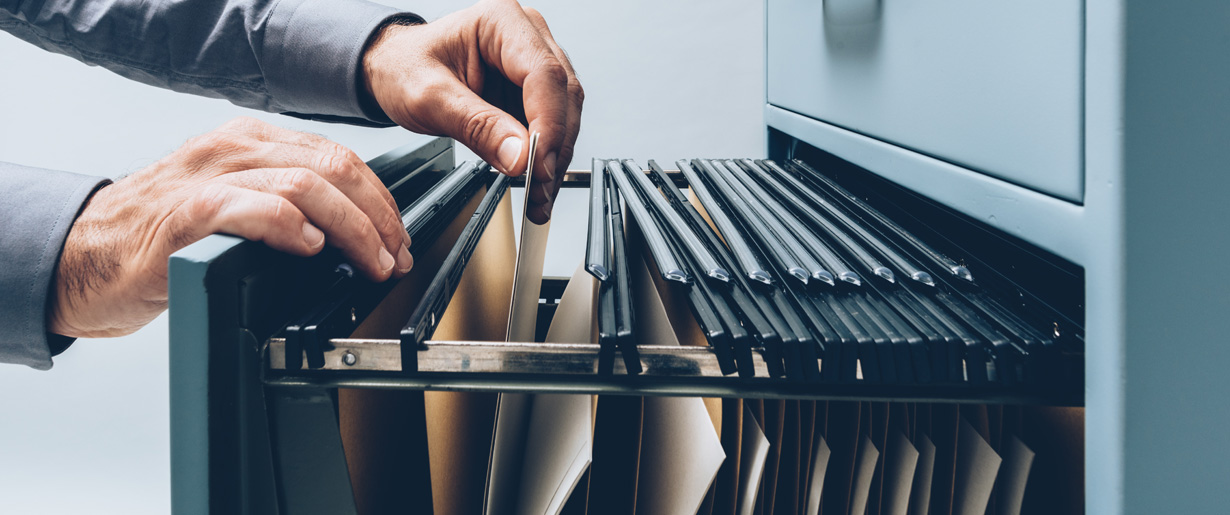 A person searching for files from a filing cabinet