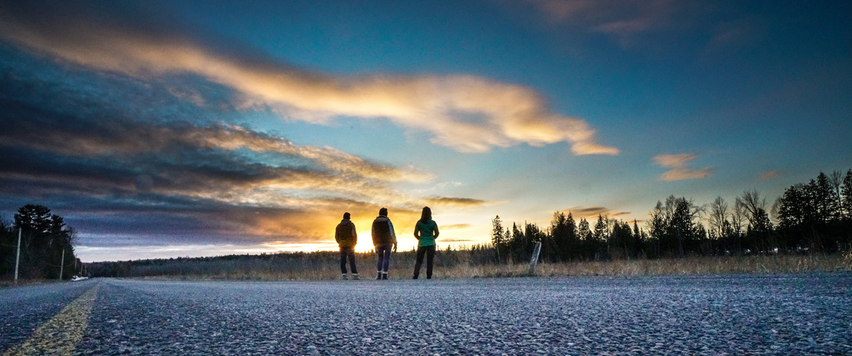 Hikers walking down a County Road at sunset