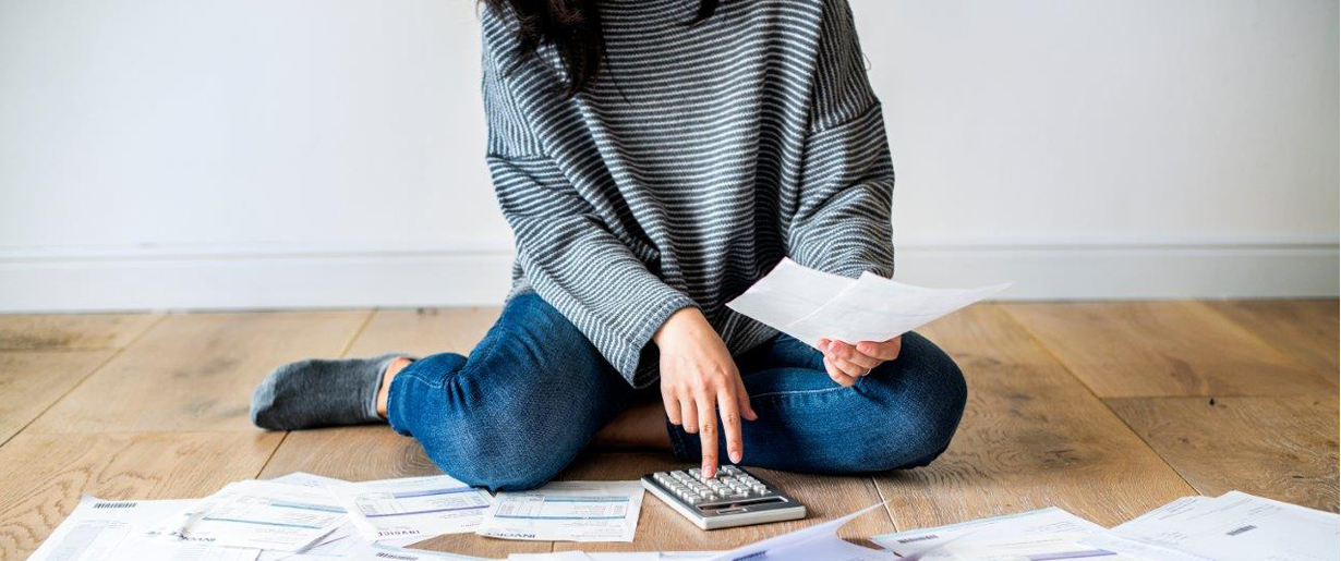 Person sitting on floor with bills surrounding her