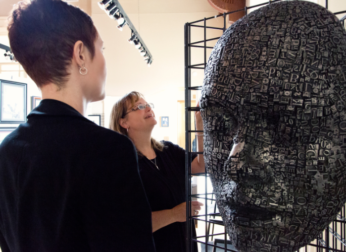 women view a statue of a head