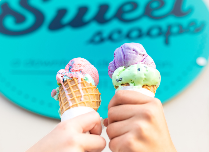 two hands holding melting ice cream cones