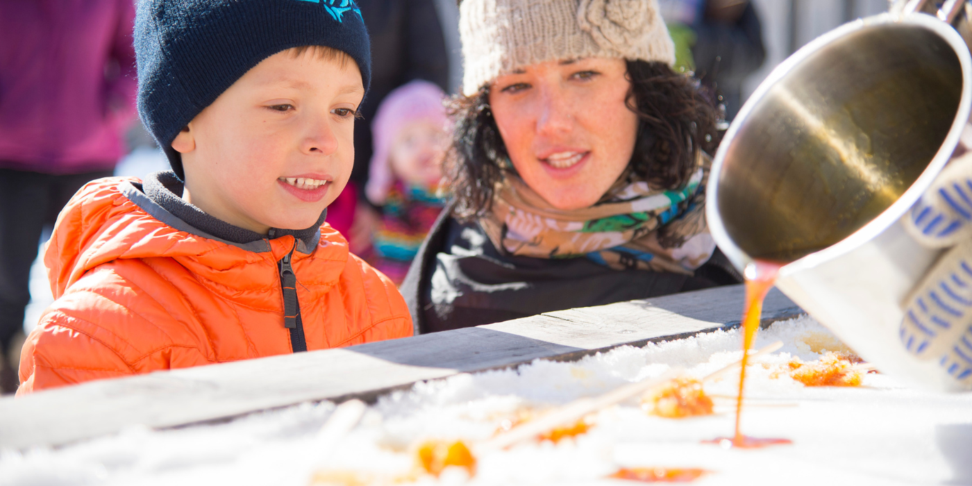 a woman and a boy try maple syrup taffy