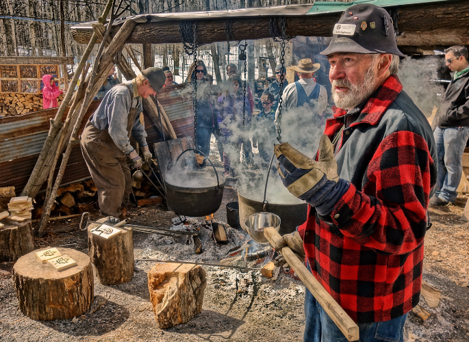a man in a plaid jacket explains the maple syrup boil
