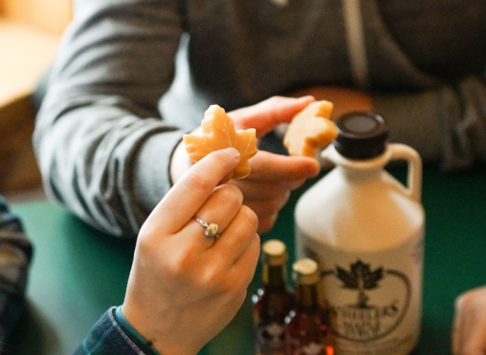 hands holding maple syrup and candies