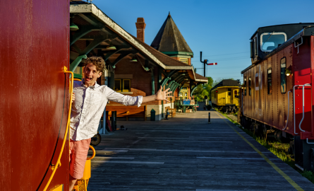 a man on a train platform waves at the camera