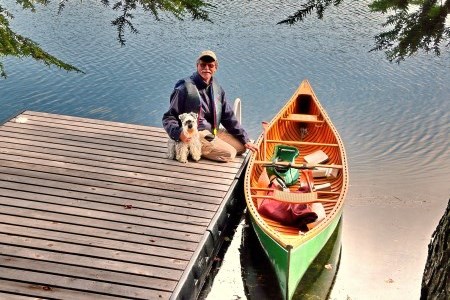 a man with his dog next to a canoe