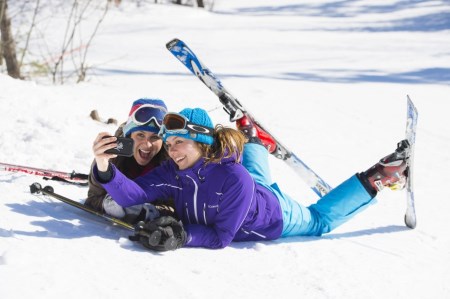 Two women taking pictures while skiing 
