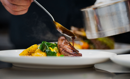 a hand pouring sauce over delicious looking food