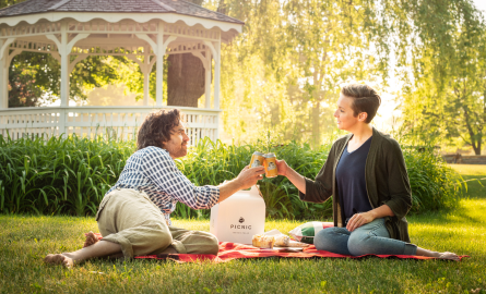 a man and a woman share a picnic in a lush green park