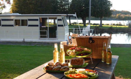 a delicious picnic spread on a table in front of a houseboat