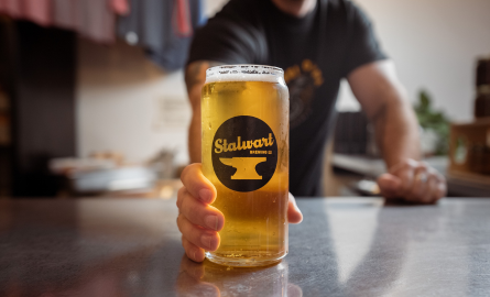 a hand serves a full glass of ale